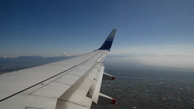Day shot of airplane flying over Taipei City, view from wing, mountains and clouds can be seen in the back