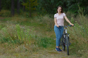 Fototapeta na wymiar Young woman riding on bicycle in the forest