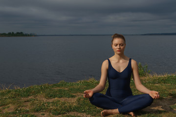 Fototapeta na wymiar Young girl in blue sportswear meditating outdoor