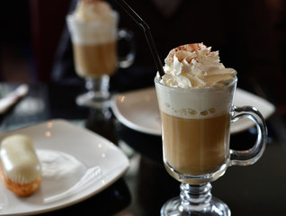 coffee with whipped cream and eclair on table in a cafe
