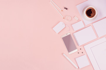 Modern minimalistic spring workspace with white blank stationery, phone, coffee on soft pastel pink background, top view, copy space.