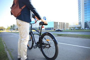 Businessman walking with bike in street after work.