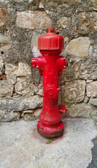 Fototapeta na wymiar Red fireplug against a stone wall