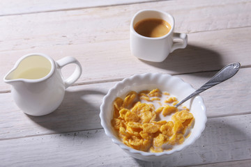 Corn Flakes cereal in a bowl, glass with milk and cap with espresso coffee. Morning breakfast.