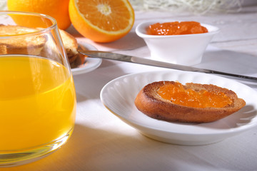 Morning Breakfast set with orange jam on bread toast and juice in glass.