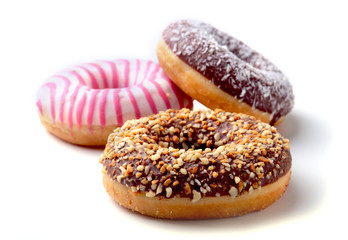 Assorted doughnuts in the glaze, colorful sprinkles and nuts on a white background.
