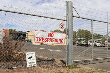 a No Trespassing and Surveillance Cameras In Use signs near the entrance of a business in an industrial area