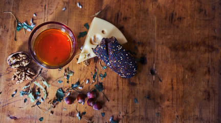 Glass with cognac, bread cheese, nuts on a wooden background