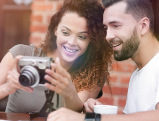 Portrait of a couple sitting down at a cafe and looking  photos