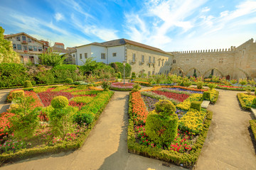 Garden outdoor alongside the eastern wing of medieval Episcopal Palace of Braga or Paco Episcopal Bracarense in Braga, Portugal. Colorful flowers in the summer season.