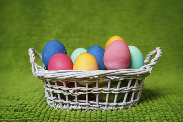 Easter background. Multicolored easter eggs in a basket on a green background. Spring Christian religious holiday of Easter