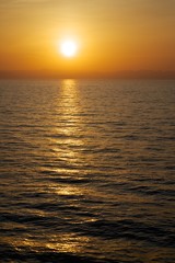 Sunset sky. View from sea. Golden reflections on the water.