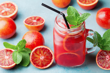 Jar glass with fruit lemonade decorated mint leaves on turquoise table. Homemade summer vitamin juice.