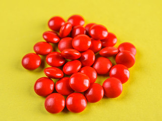 bright red pills on a yellow background.