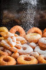 Falling powdered sugar on golden donuts ready to eat
