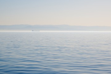Obraz premium Morning over the Black Sea. Fog on the water. Mountains on the horizon.