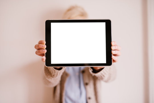 Close Up Focus View Of Tablet In A Horizontal Position With A White Editable Screen While A Blurred Woman Holding It.
