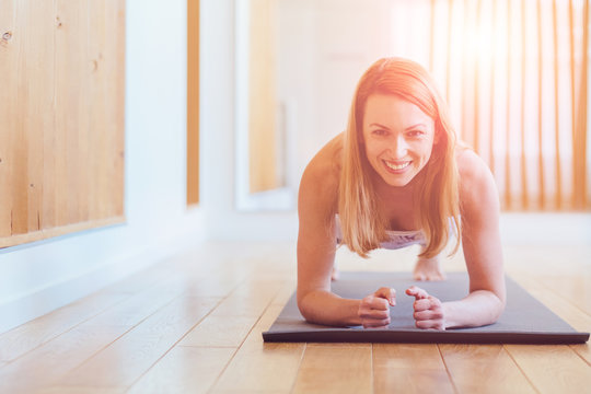 Fitness Training Sporty Positive Middle Aged Woman Doing Plank Exercise In Home Or Yoga Class Concept Exercising Workout Aerobic. Close Up. Sun Glare Effect.