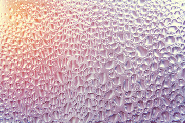 Close up view of a drops on a glass illuminated by sunlight (background, abstract, texture, toned)