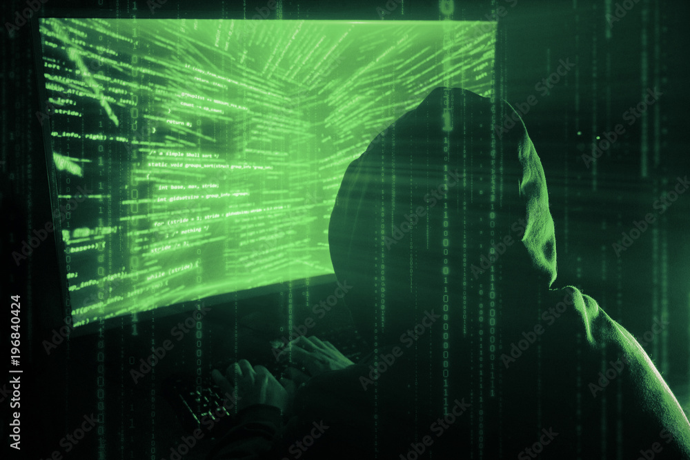Poster a man hacker in a hood in a dark room works with the program code