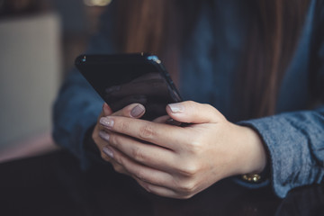Closeup image of a woman holding , using and looking at smart phone on table