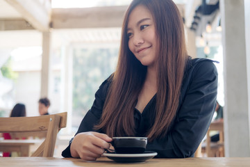 Closeup image of a beautiful asian woman holding and drinking coffee with feeling relaxed in cafe