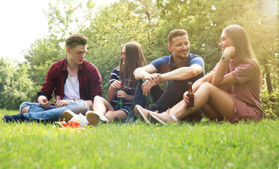 happy young friends enjoying picnic and eating.