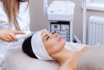 The cosmetologist makes the procedure Microcurrent therapy of the facial skin of a beautiful, young woman in a beauty salon.Cosmetology and professional skin care.
