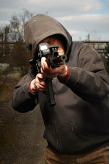 Armed man in hooden shirt pointing his automatic gun to target