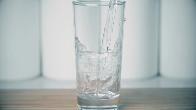 Pouring pure water into glass, super slow motion shot