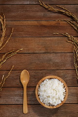 Jasmine rice in wood bowl and paddy rice on a brown wooden background beautiful Thai food