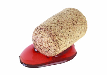 Cork lying in puddle of red wine, white background