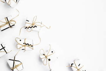 Small gift boxes of white color with black geometric patterns tied with twine. On a white background. Flat lay, Top view, copyspace