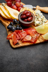 Meat plate antipasti snack - Prosciutto ham, blue cheese, melon, grapes, Olives