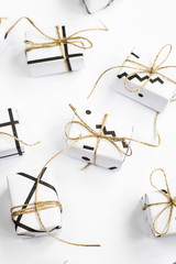 Small gift boxes of white color with black geometric patterns tied with twine. On a white background. Top view, flat lay