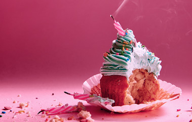 bitten muffin with cream with extinguished candles