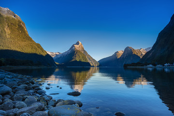 Mitre Peak with morning light, clear blue sky with the reflection in the water. Milford sound, Fiordland national park, southisland, New Zealand.