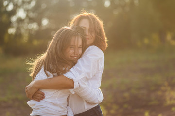 happy mother with her daughter hugging a teenager in the summer