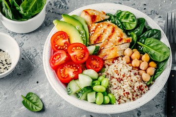 Buddha bowl with spinach salad, quinoa, chickpeas, grilled chicken, avocado, tomatoes, cucumbers,...