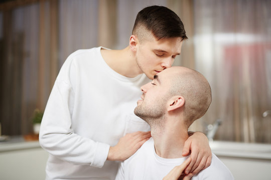 Young gay man giving his lover kiss on head in the morning after breakfast