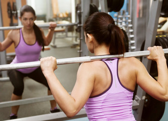 Fototapeta na wymiar girl gym lifts bar in front mirror