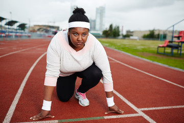 Obraz premium Serious and determined sportswoman looking forwards while standing by start line before marathon