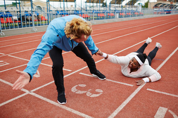 Young exhausted plus-sized woman in activewear talking to trainer pulling her towards finish line