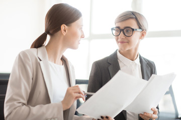 Obraz premium Two young managers or economists with papers discussing details of new contracts or financial documents