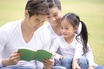 Asian family reading book together at outdoor place. People lifestyle concept.