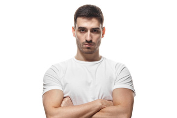 Tough guy standing with crossed arms isolated on white background. Serious young man portrait...