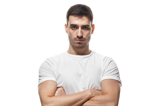 Tough guy standing with crossed arms isolated on white background. Serious young man portrait concept