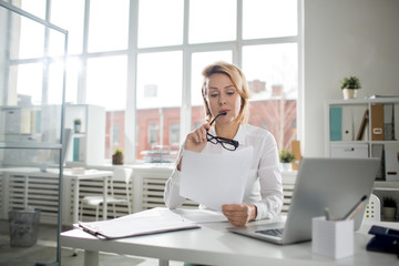 Concentrated businesswoman reading important documents at the office table