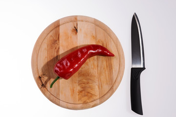 Fresh red paprika on the wooden cutting board and black knife