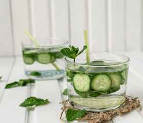 Homemade cucumber and mint lemonade in a glass on a white wooden background.